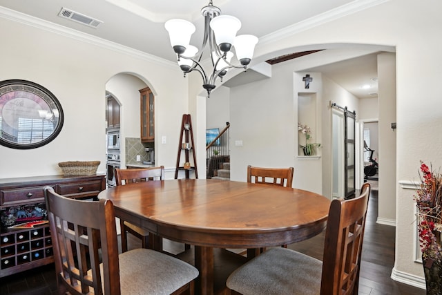 dining area with a barn door, dark hardwood / wood-style flooring, a chandelier, and ornamental molding