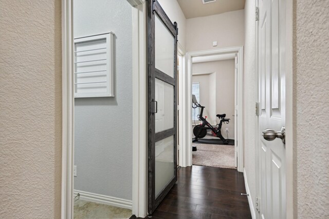 hallway featuring dark wood-type flooring and a barn door