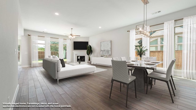 dining space featuring dark wood-type flooring and ceiling fan with notable chandelier