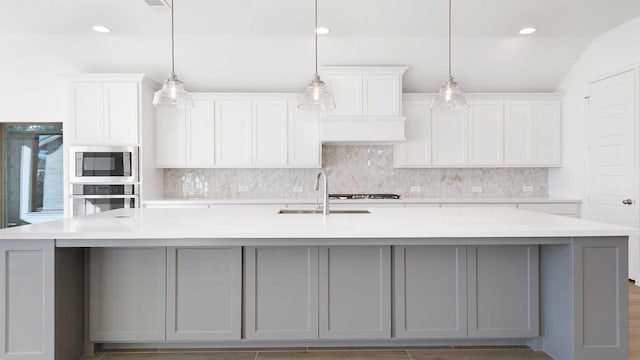 kitchen featuring appliances with stainless steel finishes, decorative light fixtures, white cabinetry, sink, and a spacious island