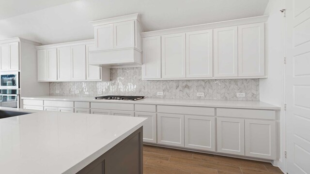 kitchen featuring white cabinetry, stainless steel gas stovetop, tasteful backsplash, and premium range hood