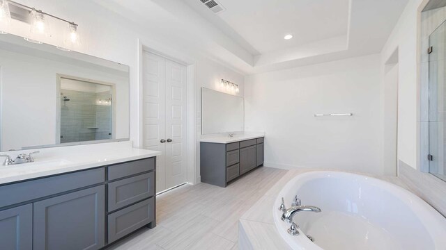 bathroom featuring vanity, plus walk in shower, and a raised ceiling