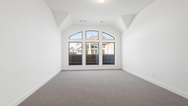 carpeted empty room with lofted ceiling