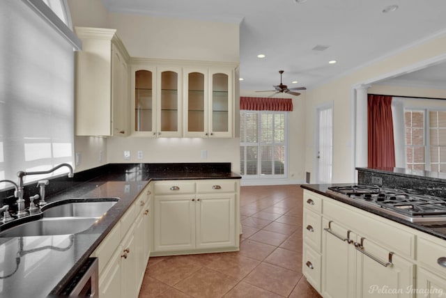 kitchen featuring sink, dark stone countertops, stainless steel gas cooktop, light tile patterned floors, and cream cabinets