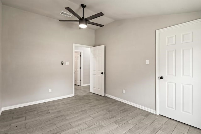 empty room with lofted ceiling, ceiling fan, and light wood-type flooring