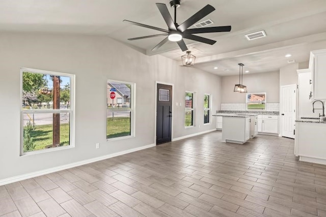 unfurnished living room featuring lofted ceiling with beams, sink, ceiling fan, and a wealth of natural light