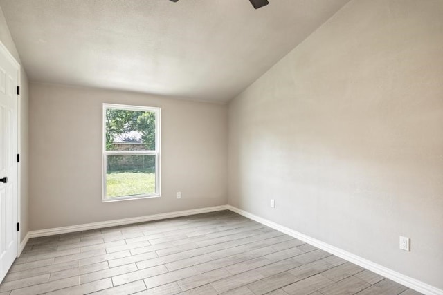 spare room featuring light wood-type flooring and vaulted ceiling