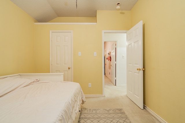 carpeted bedroom with ensuite bath, ceiling fan, and vaulted ceiling