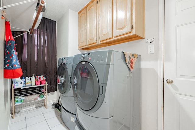 laundry area with cabinets, washer and dryer, light tile patterned floors, and a textured ceiling