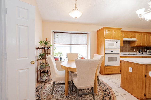 interior space with light tile patterned flooring, pendant lighting, tasteful backsplash, and white appliances