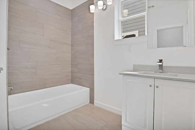 bathroom with hardwood / wood-style flooring, tiled shower / bath combo, and vanity