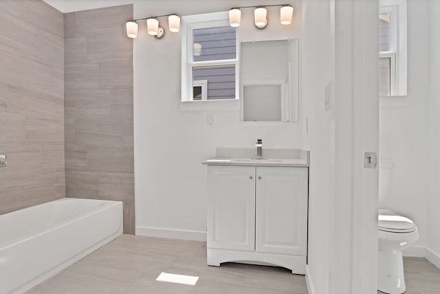 full bathroom featuring tiled shower / bath combo, toilet, and vanity