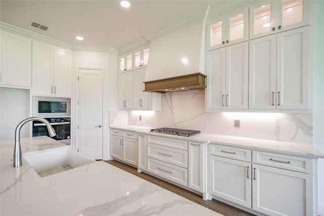 kitchen featuring white cabinetry, light stone countertops, stainless steel gas cooktop, and premium range hood