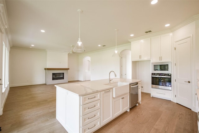 kitchen featuring sink, decorative light fixtures, stainless steel appliances, a kitchen island with sink, and white cabinets