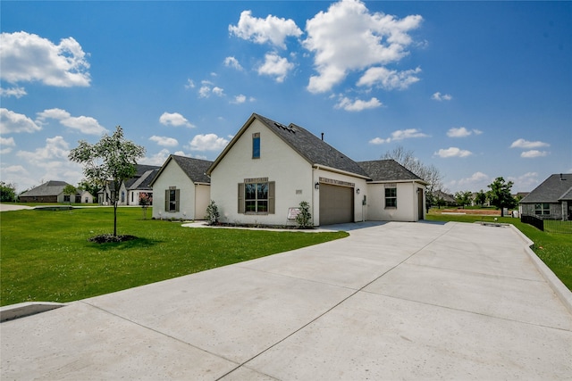 french country style house featuring a garage and a front lawn