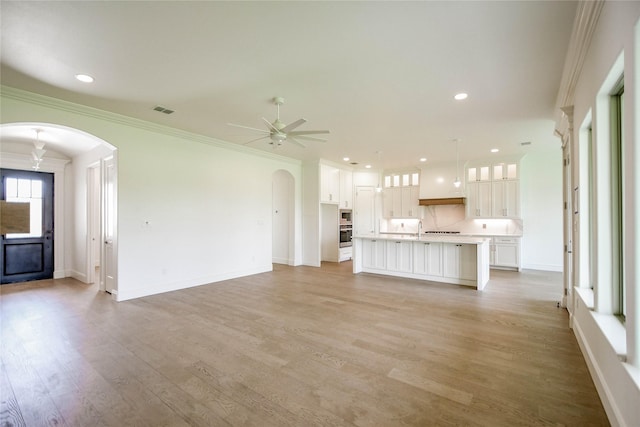 unfurnished living room featuring ceiling fan, ornamental molding, and light hardwood / wood-style floors