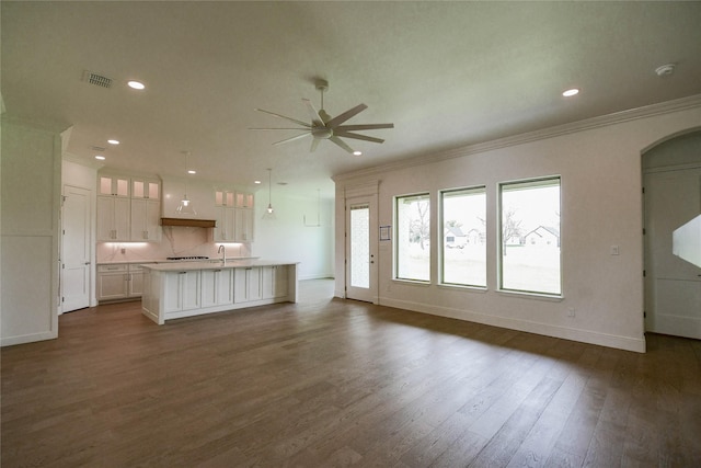 unfurnished living room featuring crown molding, ceiling fan, dark hardwood / wood-style floors, and sink