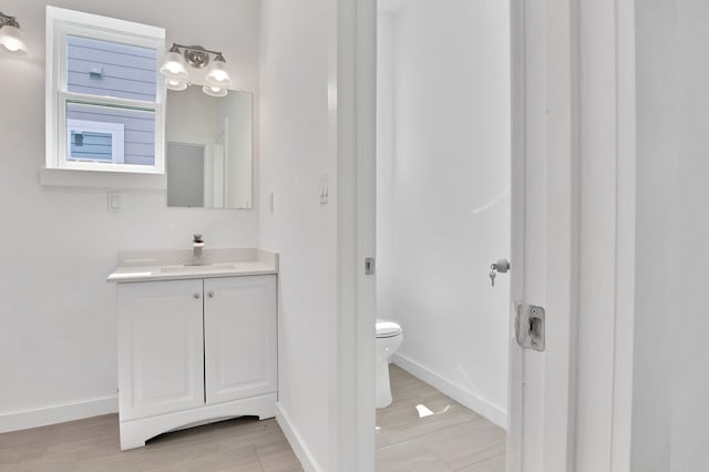 bathroom with hardwood / wood-style floors, vanity, and toilet