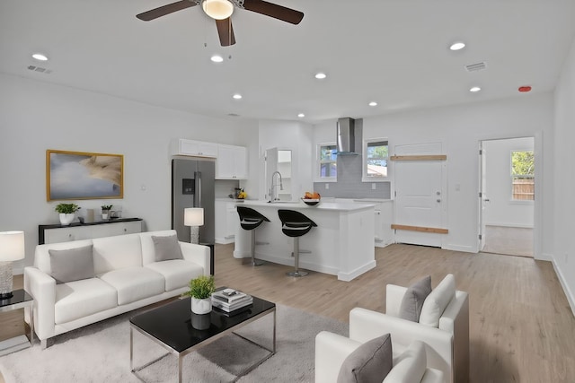 living room with light hardwood / wood-style floors, sink, a wealth of natural light, and ceiling fan