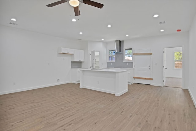 kitchen with white cabinets, a healthy amount of sunlight, light hardwood / wood-style floors, and a kitchen island with sink