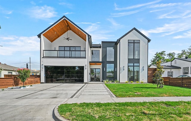 view of front of property with driveway, a balcony, ceiling fan, fence, and stucco siding