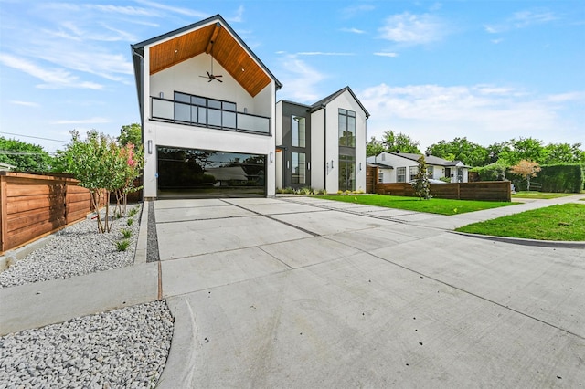 contemporary home with a balcony, fence, driveway, stucco siding, and a front lawn