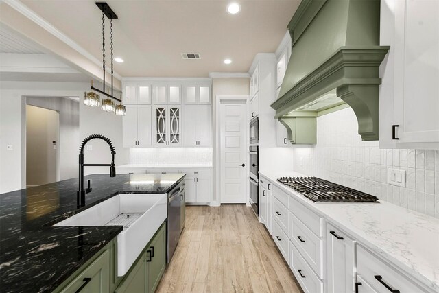 kitchen featuring appliances with stainless steel finishes, stone countertops, light hardwood / wood-style flooring, white cabinets, and hanging light fixtures