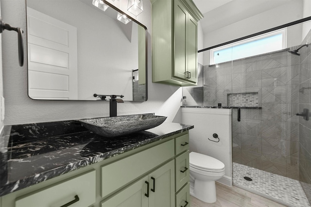 bathroom featuring hardwood / wood-style flooring, vanity, toilet, and a tile shower