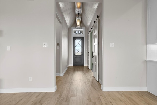 entryway featuring a barn door, wood ceiling, vaulted ceiling, and light hardwood / wood-style floors