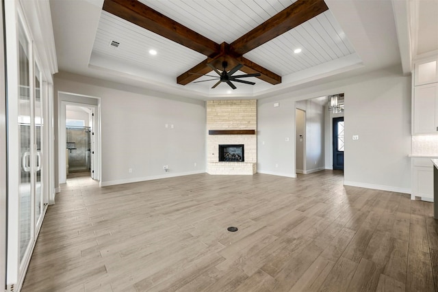 unfurnished living room featuring ceiling fan, a fireplace, beamed ceiling, light hardwood / wood-style floors, and wood ceiling