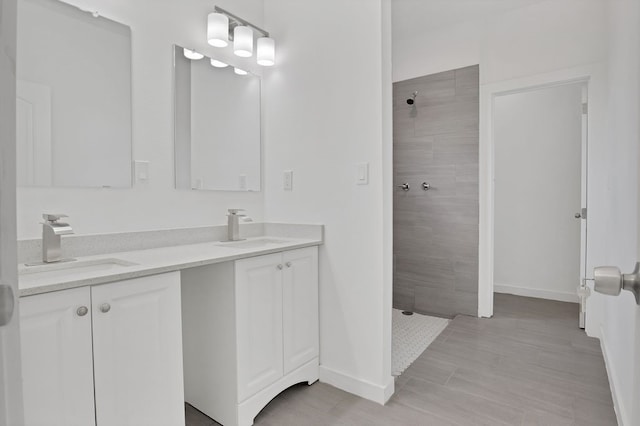 bathroom with double vanity, tile patterned flooring, and a tile shower