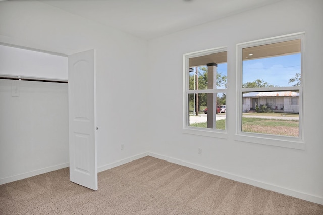 unfurnished bedroom featuring light colored carpet and a closet