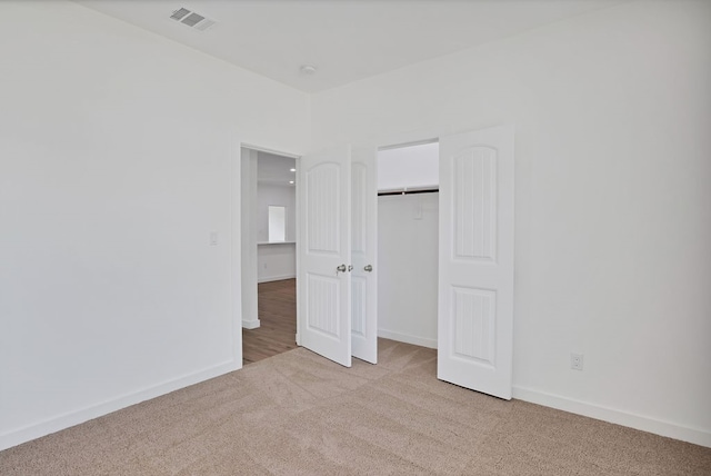 unfurnished bedroom featuring light carpet and a closet