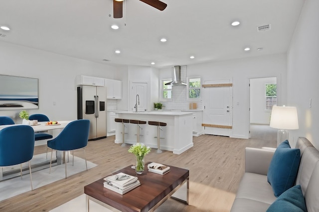 living room with plenty of natural light, sink, ceiling fan, and light hardwood / wood-style floors