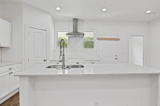 kitchen featuring wall chimney range hood, sink, dark wood-type flooring, and tasteful backsplash