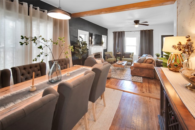 dining area featuring beam ceiling, wood-type flooring, and ceiling fan