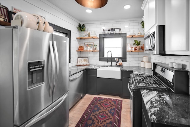 kitchen featuring white cabinetry, tasteful backsplash, stainless steel appliances, light hardwood / wood-style floors, and sink