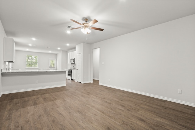 unfurnished living room featuring dark wood-type flooring and ceiling fan