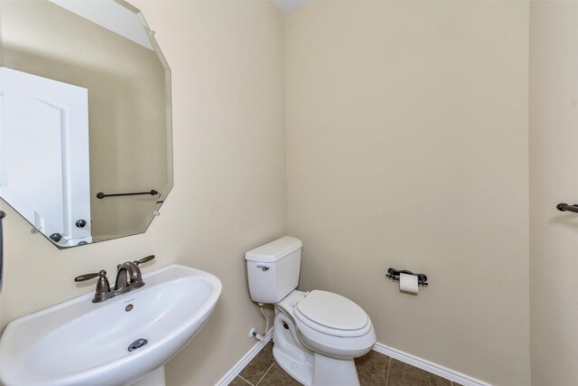 bathroom with toilet, tile patterned floors, and sink