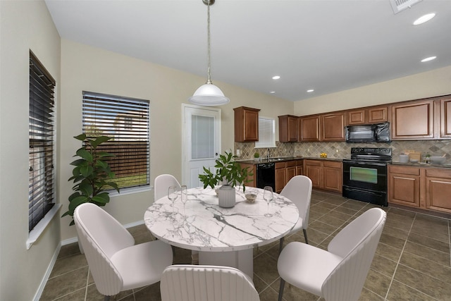 kitchen featuring tasteful backsplash, decorative light fixtures, dark tile patterned flooring, and black appliances