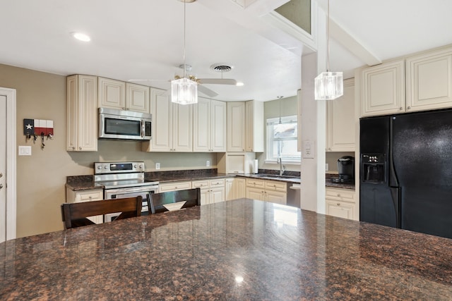 kitchen with ceiling fan, dark stone counters, appliances with stainless steel finishes, and cream cabinets