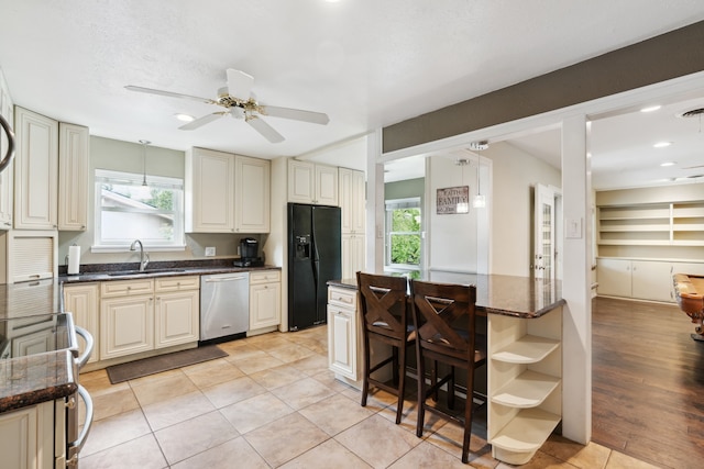 kitchen featuring ceiling fan, dishwasher, black fridge, and plenty of natural light