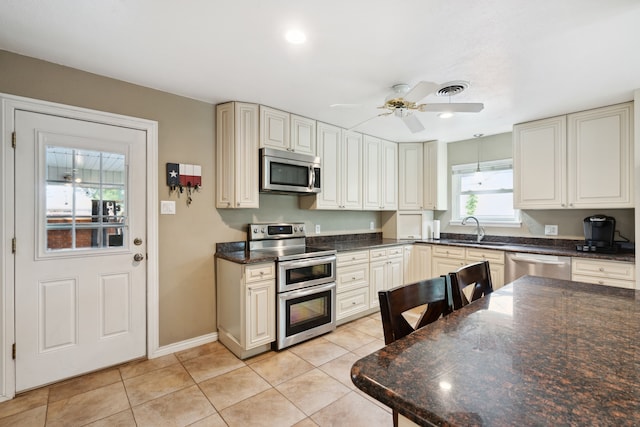 kitchen with light tile patterned floors, cream cabinets, ceiling fan, stainless steel appliances, and sink