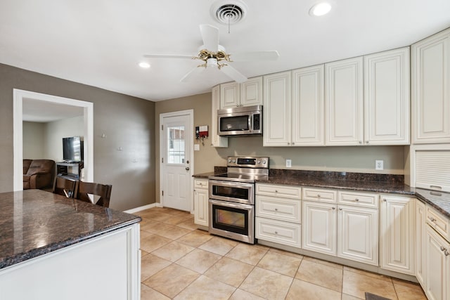 kitchen featuring light tile patterned flooring, dark stone countertops, ceiling fan, and stainless steel appliances