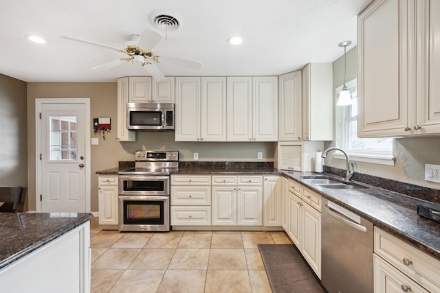 kitchen featuring light tile patterned flooring, ceiling fan, sink, dark stone countertops, and appliances with stainless steel finishes