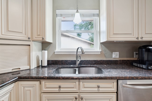 kitchen featuring dishwasher, dark stone countertops, sink, and cream cabinets