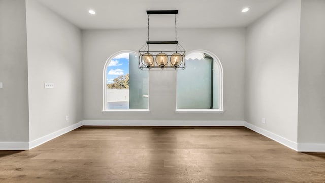 unfurnished dining area with an inviting chandelier and wood-type flooring