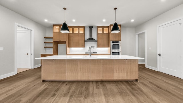 kitchen featuring a spacious island, dark hardwood / wood-style floors, hanging light fixtures, and wall chimney exhaust hood