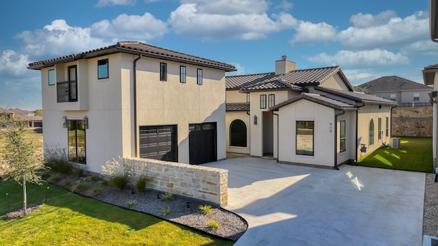 mediterranean / spanish home featuring a garage, central AC, and a front yard