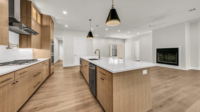 kitchen featuring sink, pendant lighting, a large island, light hardwood / wood-style floors, and wall chimney range hood